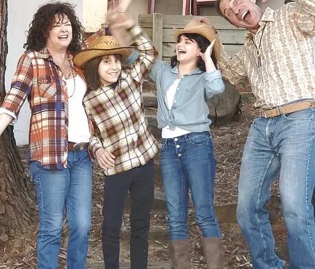 a family of four with mom, dad and two kids dressed in flannel shirts with their hands in the air