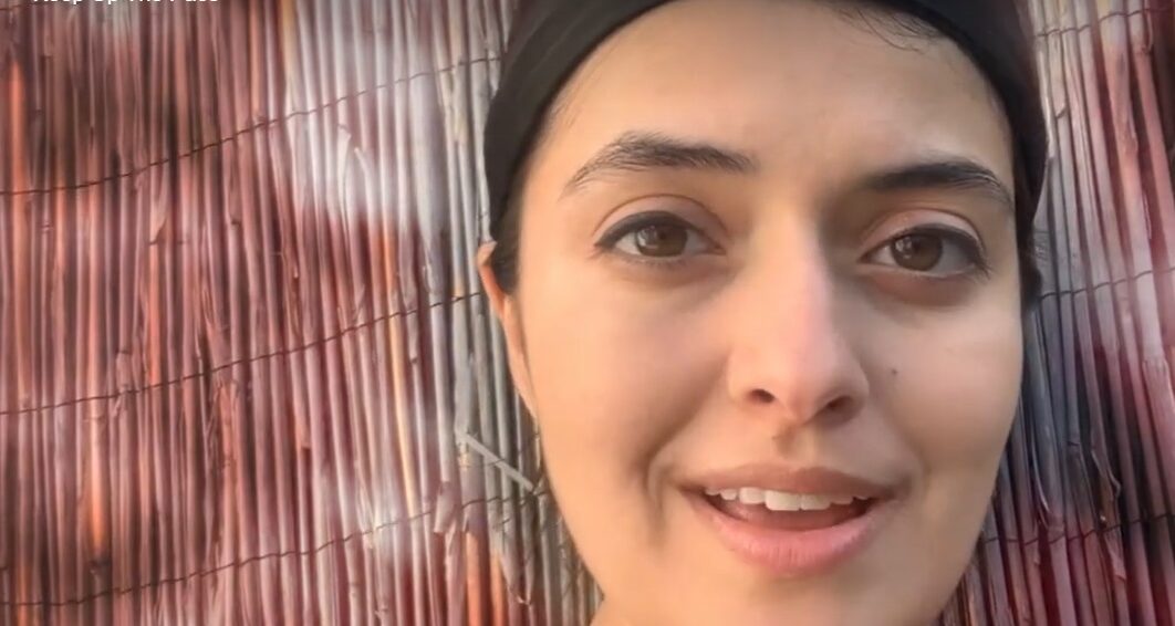 a close up of a woman's face against a bamboo screen