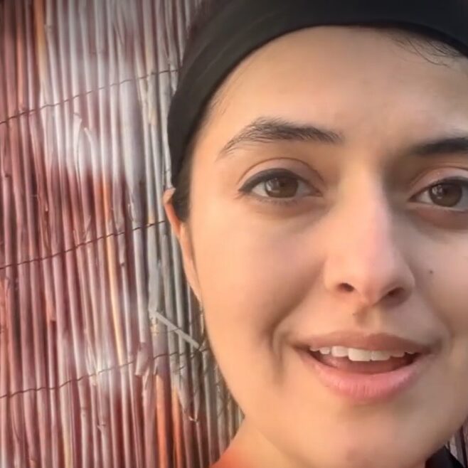 a close up of a woman's face against a bamboo screen