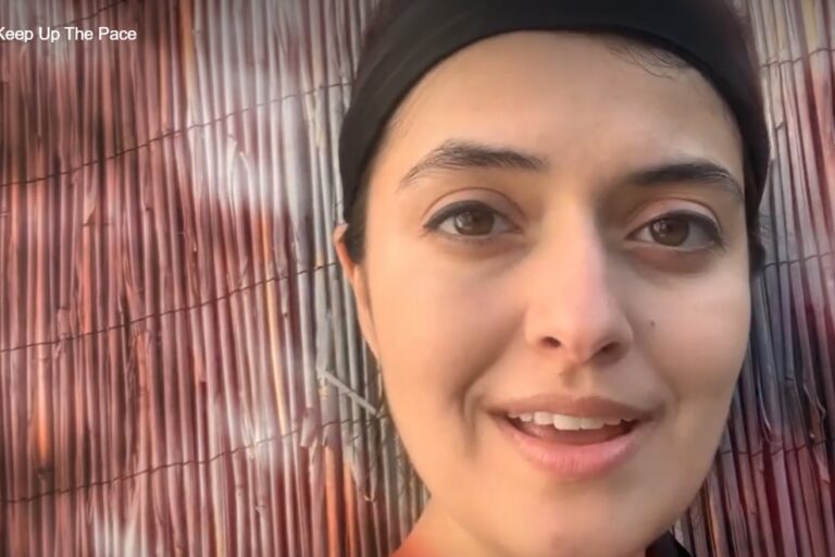 a close up of a woman's face against a bamboo screen