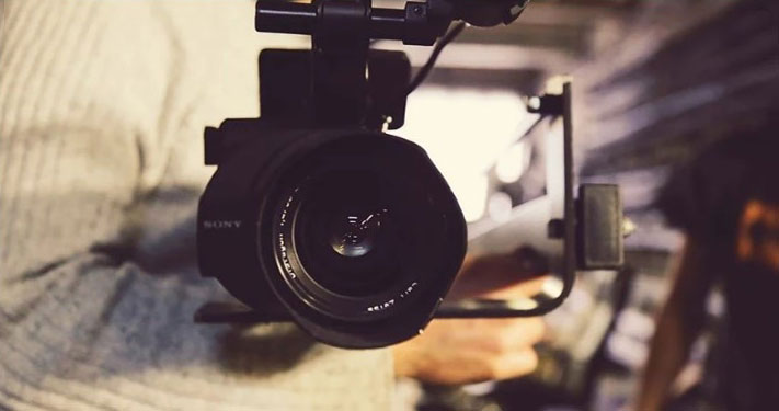 A person holding a professional camera in their arms