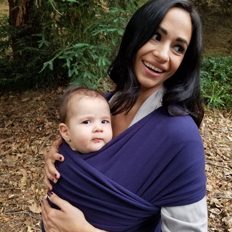 White woman holding her baby up against her chest in a cloth