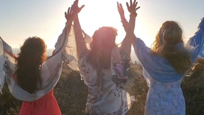 Three women raising hands up towards the sky