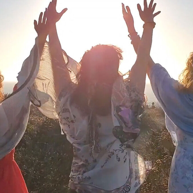 Three women raising hands up towards the sky