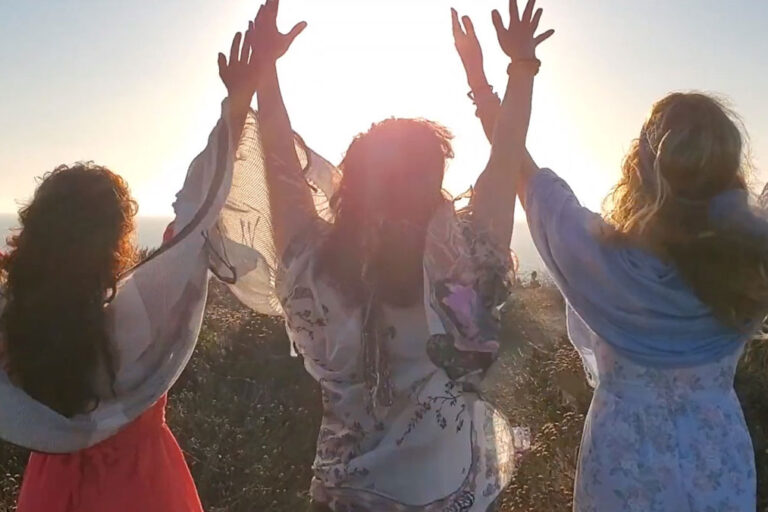 Hands-up-in-song Three women raising hands up towards the sky