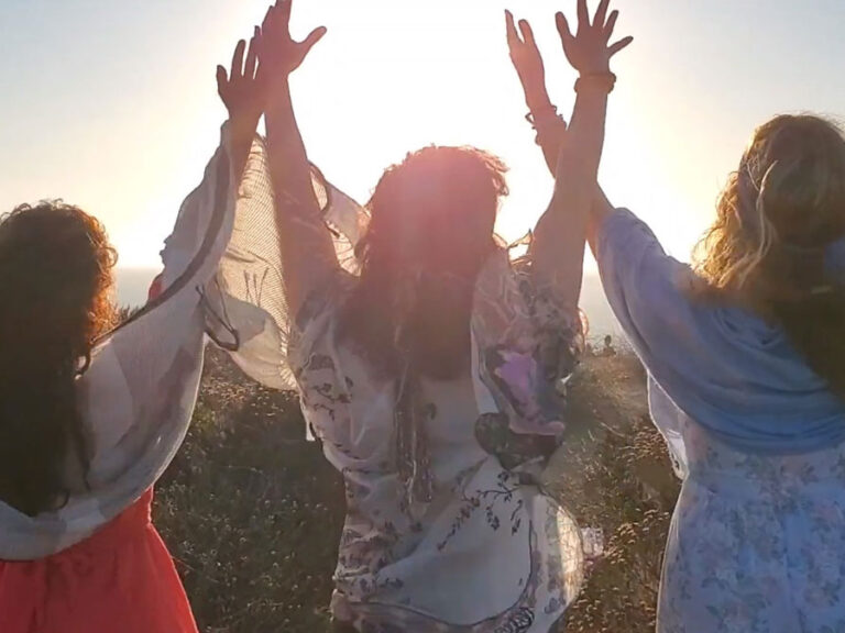 Three women raising hands up towards the sky