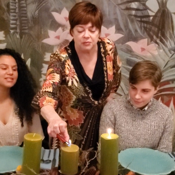 Mom lighting candles with her son and his friend