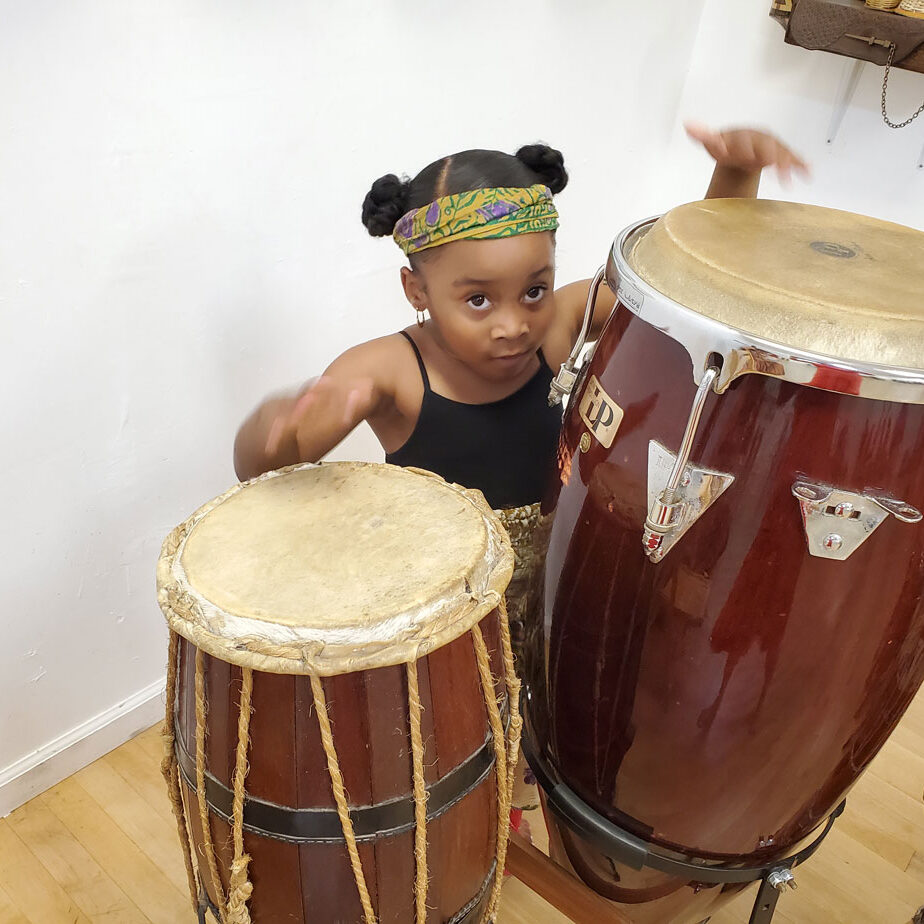Little black girl playing the bongos